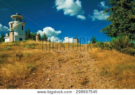 Rocky Trail Going To Lighthouse On Hill Covered By Green Grass And Trees, At The Highlands Of Serra 