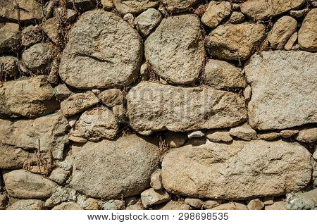 Close-up Of Old Wall Made Of Large Rough Stones Forming A Charming Background, In A Sunny Day At Unh