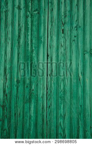 Close-up Of Worn Planks Of Wood In An Old Green Door Forming A Singular Background, In A Sunny Day A
