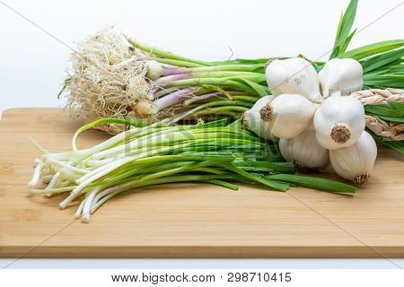 Head Of Garlic And Green Garlic On Cutting Board Preparated For Cooking. Close-up Photo With Selecti