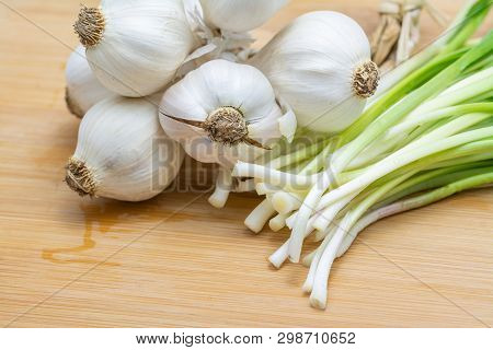 Head Of Garlic And Green Garlic On Cutting Board Preparated For Cooking. Close-up Photo With Selecti