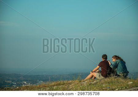 Couple Of People Sitting On Green Lawn At Sunset