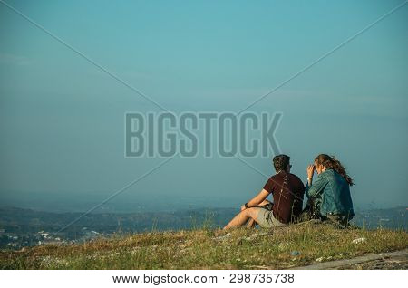 Couple Of People Sitting On Green Lawn At Sunset