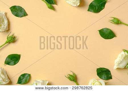 Flowers Composition. Frame Made Of Roses Flowers And Green Leaves On Pastel Yellow Background. Flat 