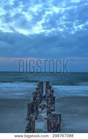 Moonset At Dawn Over A Dilapidated Pier On The Beach In Port Royal
