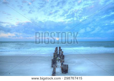 Moonset At Dawn Over A Dilapidated Pier On The Beach In Port Royal