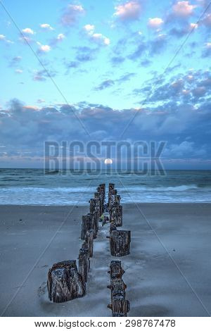 Moonset At Dawn Over A Dilapidated Pier On The Beach In Port Royal