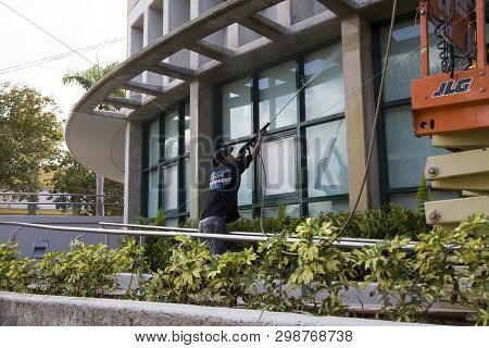 Bayamon/puerto Rico - February 26, 2019: Hispanic Man Uses High Pressure Washer Machine To Clean Ext