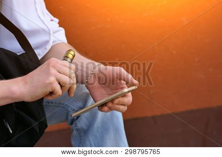 Man Soars Electronic Cigarette While Sitting With The Phone Close-up