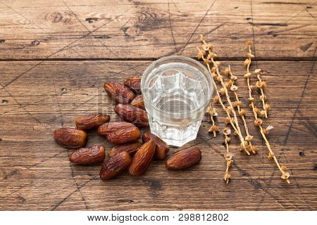 Dried Dates Fruits And A Glass Of Water On A Wooden Table. Traditional Fast Breaking, Muslims Evenin