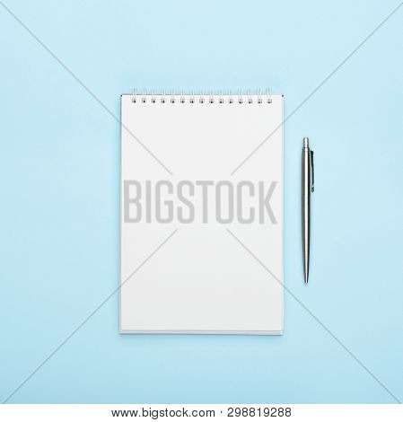 White Notepad With Metal Pen On A Blue Background. Office, Copy Space, Mock Up, Template, Top View, 