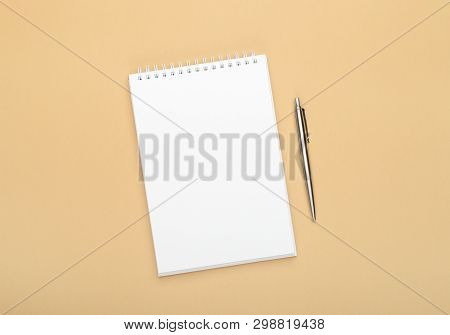 White Notebook With Steel Pen On A Brown Background. Office, Save Space, Mock Up, Template, Top View