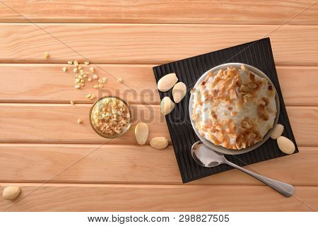 Almond Ice Cream Cup Decorated With Almond Pieces On A Plate On A Wooden Table. Horizontal Compositi