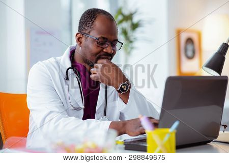 Dark-skinned Doctor Wearing Glasses And Watch Feeling Thoughtful
