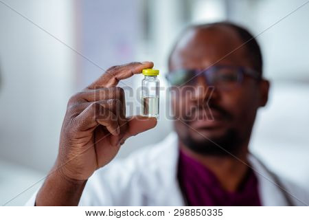 Dark-skinned Doctor Holding Little Ampoule With Medicine