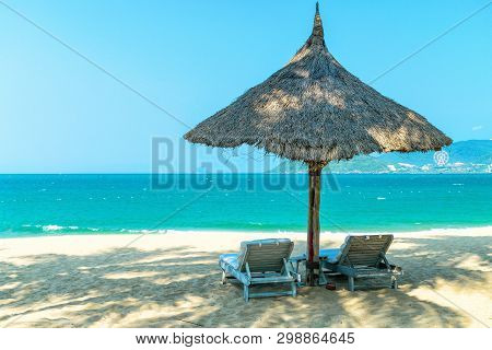 Two Loungers Under Strawy Parasol On Sandy Beach For Relax