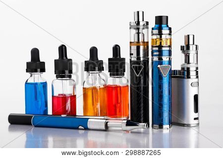 Electronic Cigarettes And Bottles With Vape Liquid On White Background