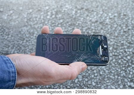 Smartphone With A Broken Screen Glass In Hand Of Young Man.