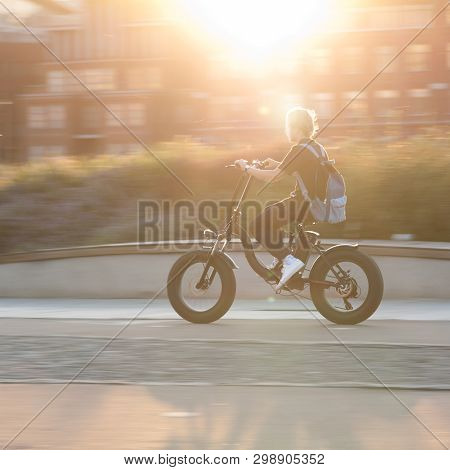 The Boy On A Bicycle Is Driving Around The City On A Sunny Summer Evening