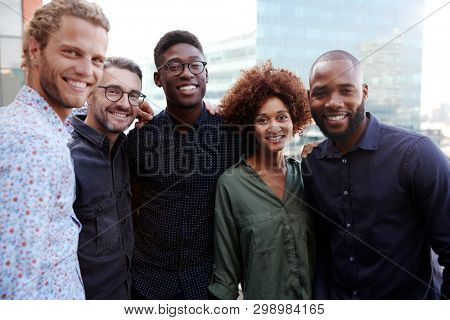 Happy creative business colleagues smiling to camera outdoors, waist up, close up