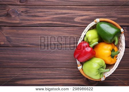 Fresh Pepper In A Basket On Brown Background. Red, Green, Yellow Paprika On Table.
