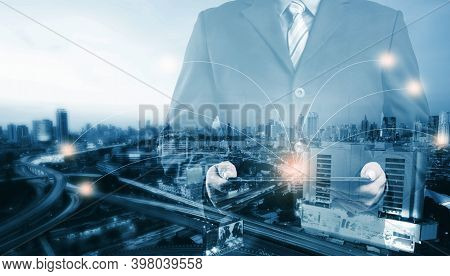 Double Exposure Of Success Businessman Using Digital Tablet With City Landscape Background And Netwo