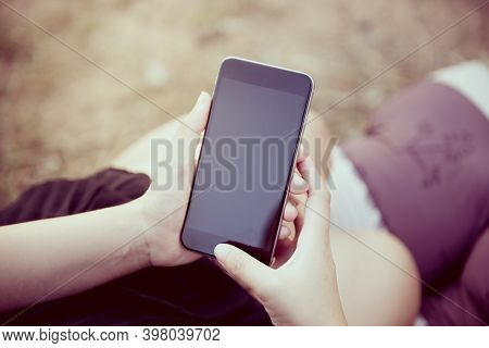 Woman With Smartphone Outdoors In Park. Closeup Of Female Hands And Smart Phone On Black Screen ,sun