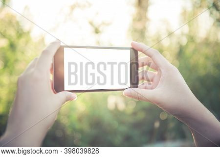 Woman With Smartphone Outdoors In Park. Closeup Of Female Hands And Smart Phone On White Screen ,sun