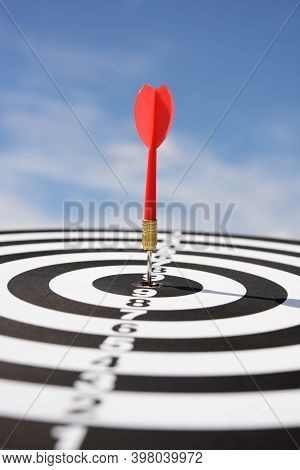 Red Dart Arrow Hitting In The Target Center Of Dartboard With Blue Sky Background