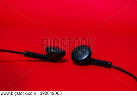 Just A Pair Of Black Headphones Pulled Together On A Simple Red Background With The Details In View 