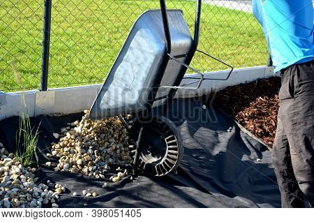 Delivery Of Gray River Pebbles Like Mulch To Flower Beds In The Garden Using A Wheelbarow From The B