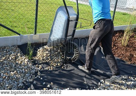 Delivery Of Gray River Pebbles Like Mulch To Flower Beds In The Garden Using A Wheelbarow From The B