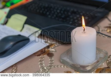 A Lighted White Candle, A Computer Mouse, Writing Sheets, The Edge Of A Laptop. Workplace Of A Magic