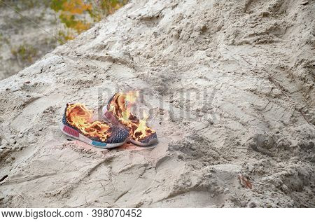Burning Sports Sneakers Or Gym Shoes On Fire Stand On Sandy Beach Coast. Athlete Burned Out. Physica