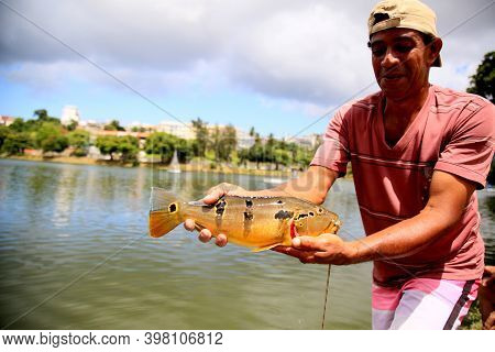 Salvador, Bahia Brazil - December 4, 2020: Fisherman Shows The Tucunare Fish That He Fished In The W
