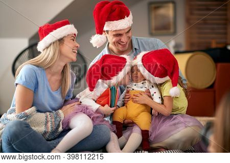 Happy parents spening Christmas time together with their kids at home