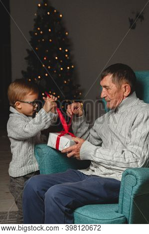 Elderly Grandfather And His Little Grandson Give And Open A Chri