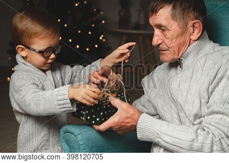 Elderly Grandfather And His Little Grandson Give And Open A Chri