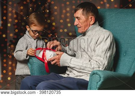 Elderly Grandfather And His Little Grandson Give And Open A Chri