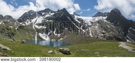 Panoramic View Of Turquoise Blue Mountain Lake Grunausee In Alpine Landscape With Green Meadow And S