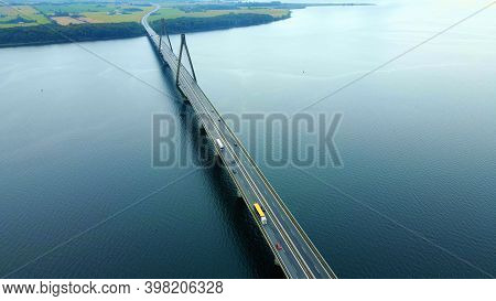 Large Highway Bridge Spanning Over A Bay, With Cars And Trucks Driving. Aerial View.