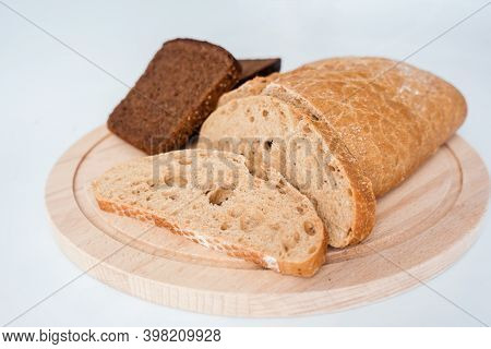 Two Types Of Cutted Into Chunks Rye Coarse Bread On A Round Wooden Board. Selective Focus.close Up.