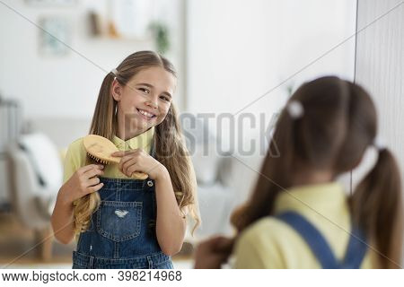 Pretty Girl. Portrait Of Female Teenager Standing In Front Of A Mirror And Brushing Her Long Hair, H