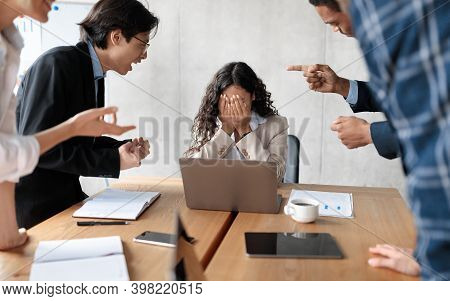 Workplace Conflict And Bullying. Aggressive Coworkers Yelling At Victimized Businesswoman Sitting At