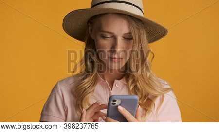 Portrait Of Girl In Hat Intently Choosing Goods Online On Smartp