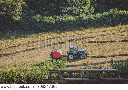 Tractor Working On The Farm In The Restormel Castle Surrounding Landscape., Uk.