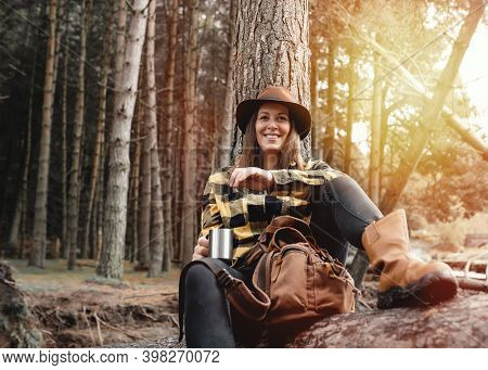 Woman In Yellow Shirt And Hat Siting On The Felled Tree In The Autumn Forest