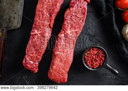 Organic Denver Steak Near Butcher Knife With Pink Pepper And Rosemary. Black Background. Top View Cl
