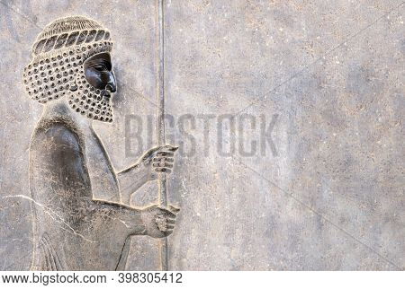 Ancient wall with bas-relief - assyrian warrior with spear, Persepolis, Iran. UNESCO world heritage site. Horizontal background with embossed image persian bearded man. Copy space for text