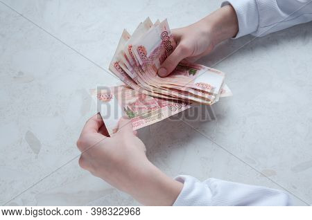 Women's Hands Hold A Bundle Of Large Bills Of Five Thousand Rubles Over The Table